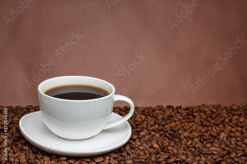 white cup of coffee on a brown background on coffee beans