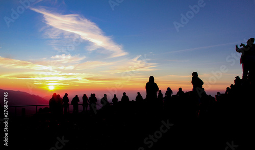 Colorful sunrise with the silhouettes of many people on top of a mountain in Flores, south-east Asia.