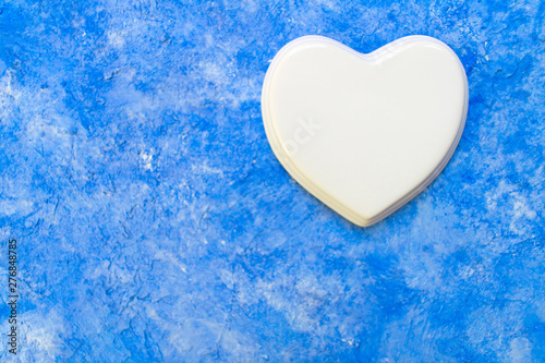 White porcelain heart on a sky blue background. Copy space