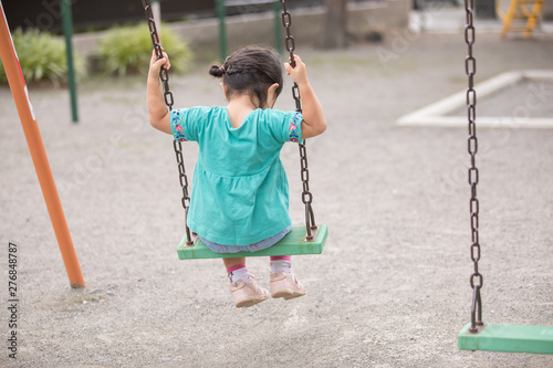 ブランコに座っている幼児の女の子が一人で俯いている photo