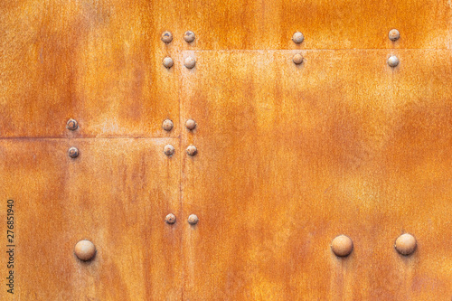 Rusty metal wall texture from sheets, background. Rusty red iron wall with large rivets.