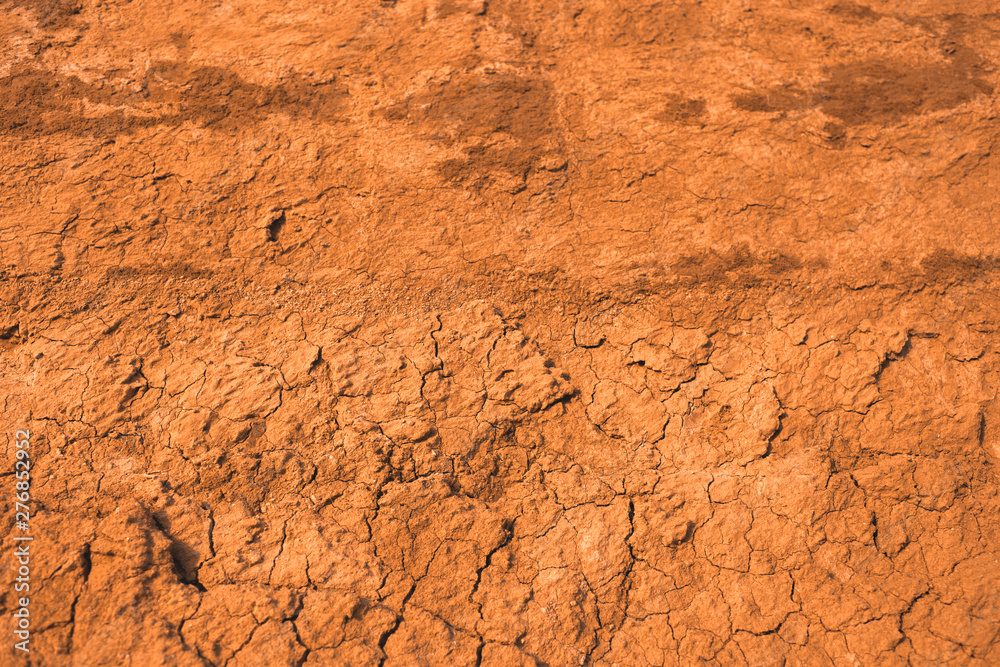 The surface of the cracked dried clay background. Brown and cracked soil background. Clay. Ocher.