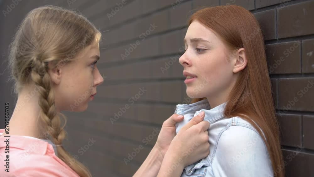 Female student threatening frightened peer pushing wall, psychological pressure Female student threatening frightened peer pushing wall, psychological pressure