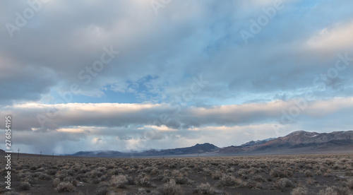 Storm clouds above mountains with cars traveling in the distance