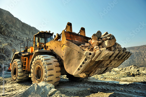 Wheel loader machine unloading rocks in the open-mine of iron ore