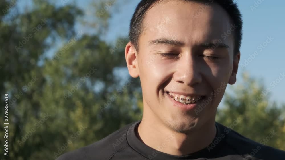Young boxer preparing for training in the park. The athlete approaches the camera and smiles. Dental braces Young boxer preparing for training in the park. The athlete approaches the camera and smiles. Dental braces