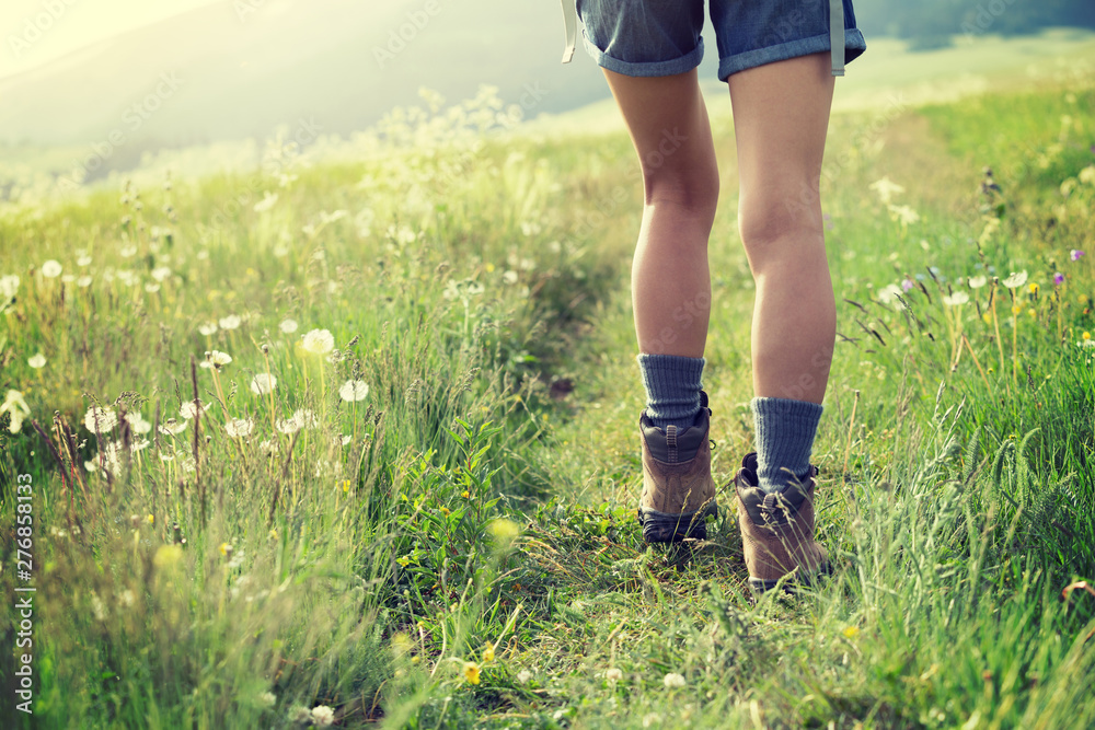 Young woman hiker walking on trail in grassland Young woman hiker walking on trail in grassland