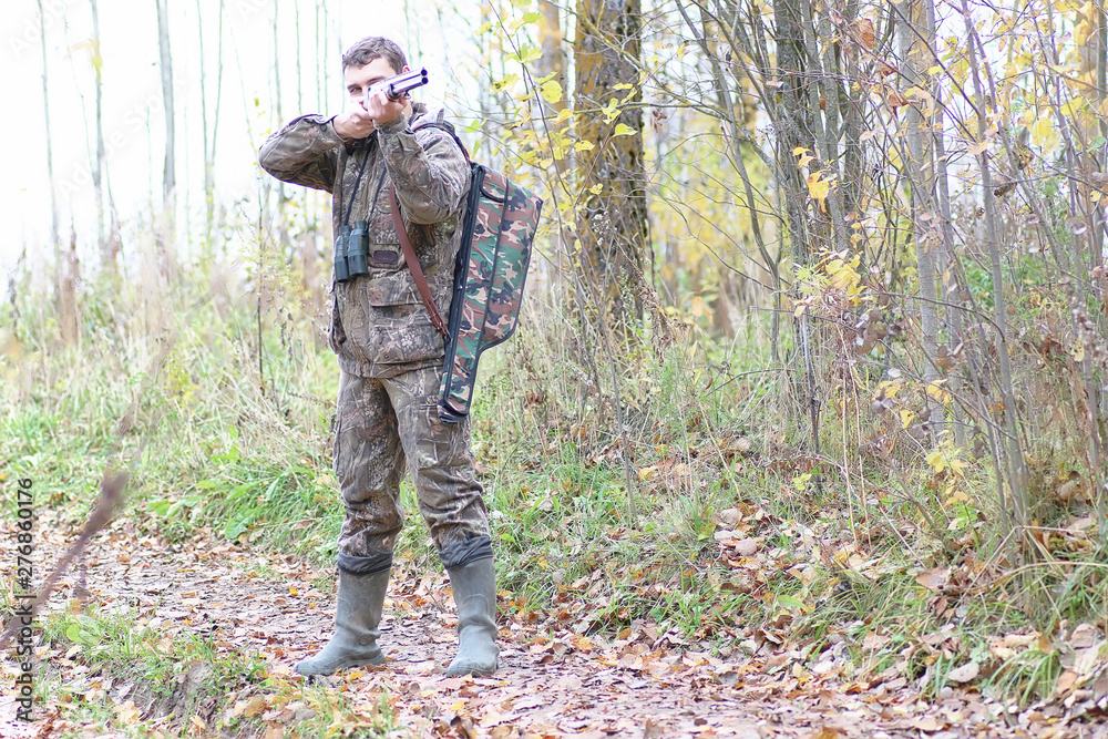 Man in camouflage and with guns in a forest belt on a spring hunt