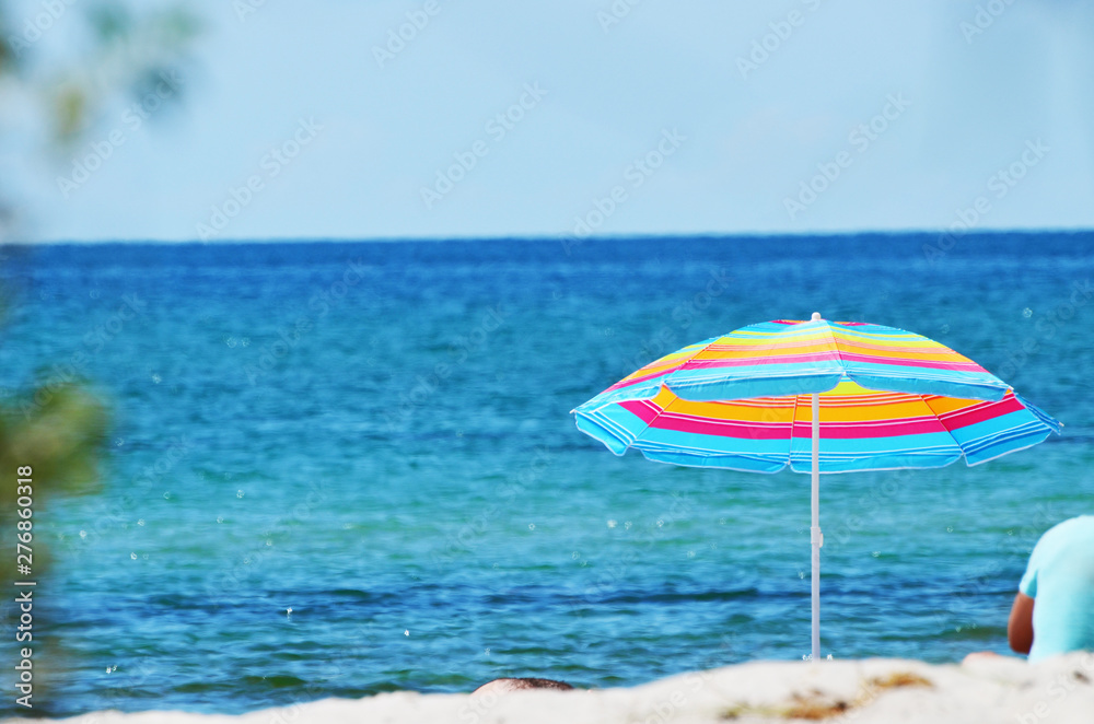 Stripped beach umbrella on the tropical beach. Relaxing summer background