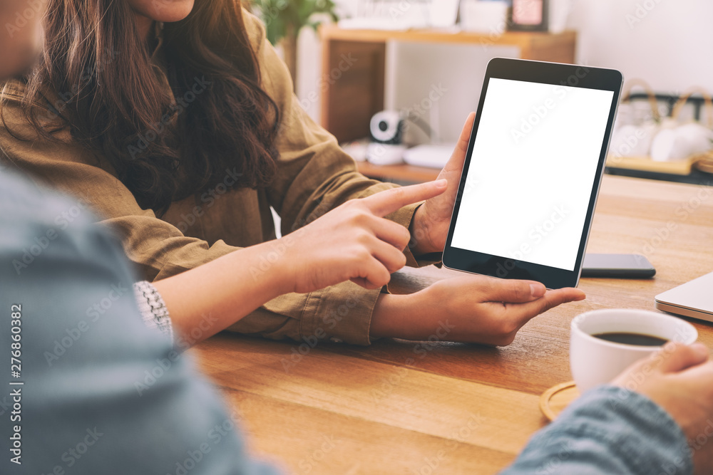 People using and looking at the same mockup tablet pc on wooden table together People using and looking at the same mockup tablet pc on wooden table together