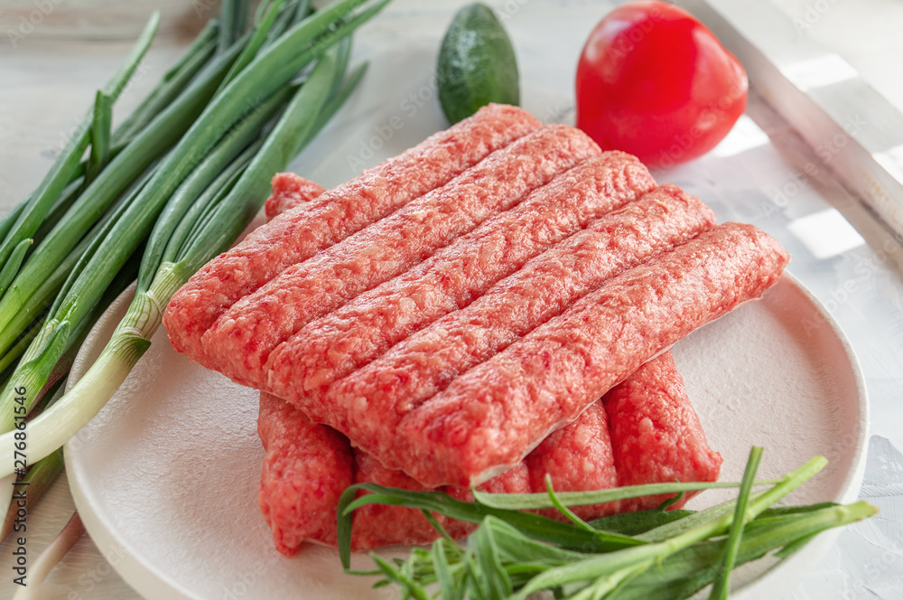 Chevapchichi is a national Balkan dish. Close up a row of fresh raw beef kebabs