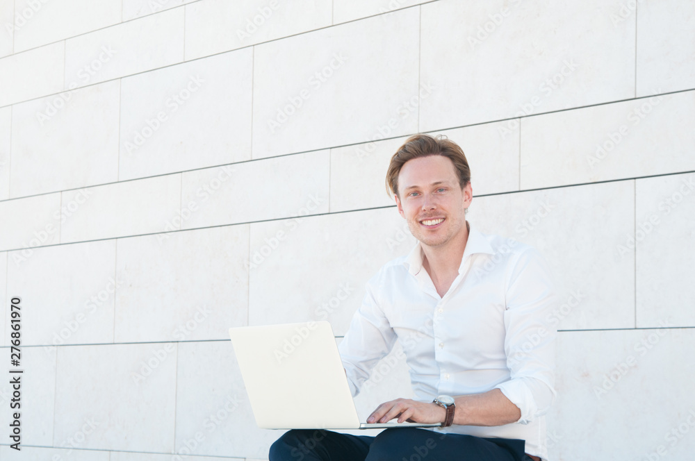 Portrait of happy programmer working outdoors. Smiling handsome young software developer working on laptop. Freelance concept Portrait of happy programmer working outdoors. Smiling handsome young software developer working on laptop. Freelance concept