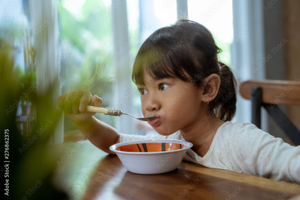 asian beautiful toddler girl having breakfast by herself in the morning at dining room asian beautiful toddler girl having breakfast by herself in the morning at dining room