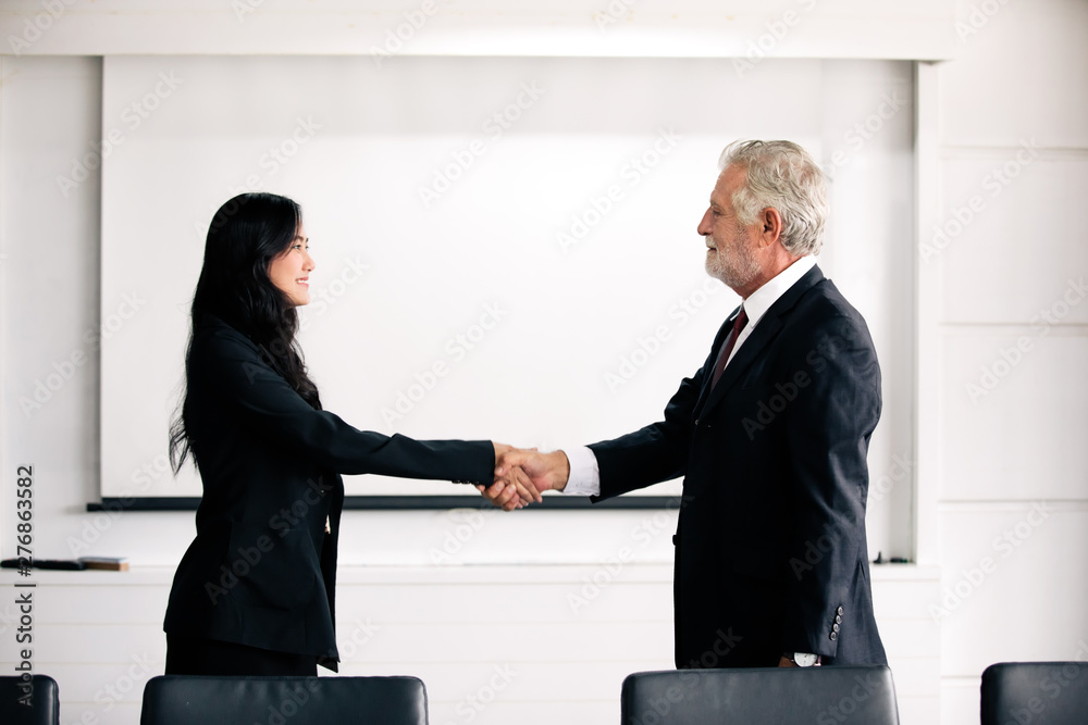 Business people shaking hands and smiling their agreement to sign contract and finishing up a meeting Business people shaking hands and smiling their agreement to sign contract and finishing up a meeting