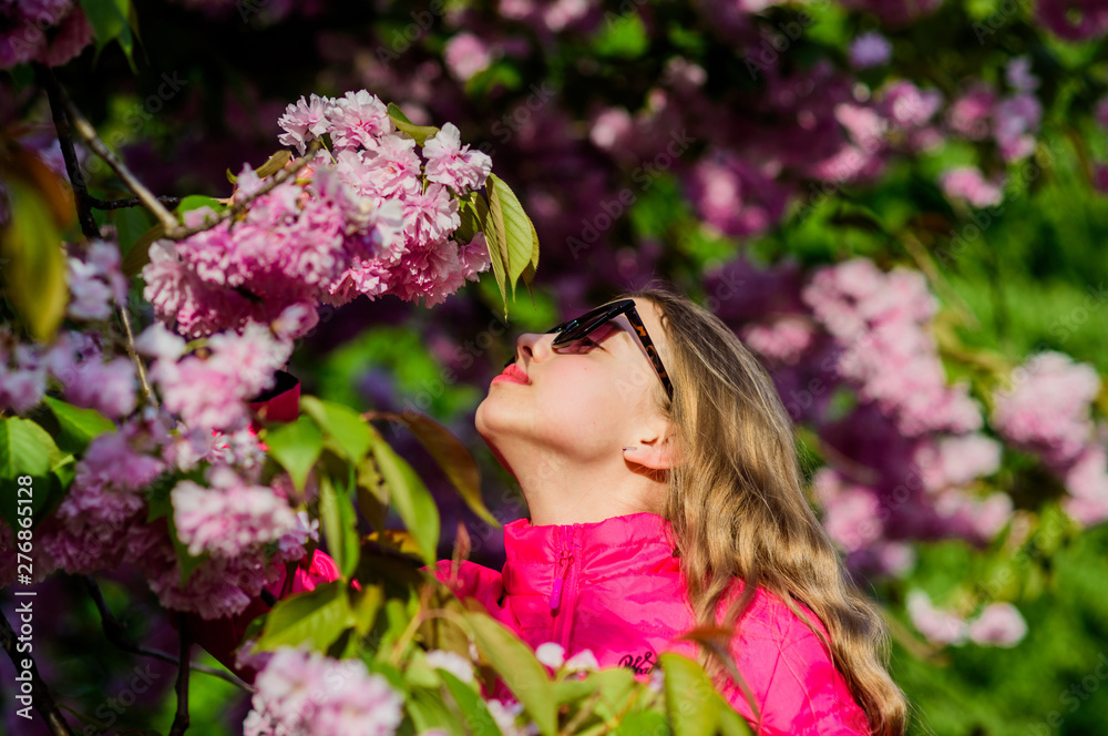 Sakura tree blooming. Small girl child in spring flower bloom. Enjoy smell of tender bloom. Sakura flower concept. Gorgeous flower and female beauty. Natural cosmetics for skin. Girl in cherry flower