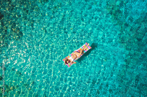 Turquoise ocean water and relaxed swimming woman, aerial drone shot. © ZoomTeam