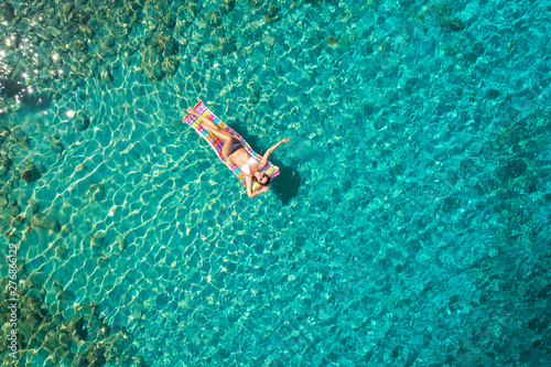 Turquoise ocean water and relaxed swimming woman, aerial drone shot. photo