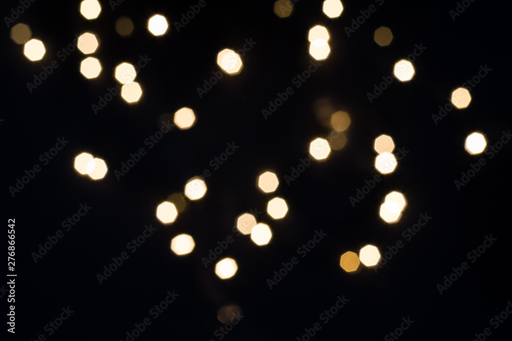 Gold bokeh lights falling on black. Holiday concept