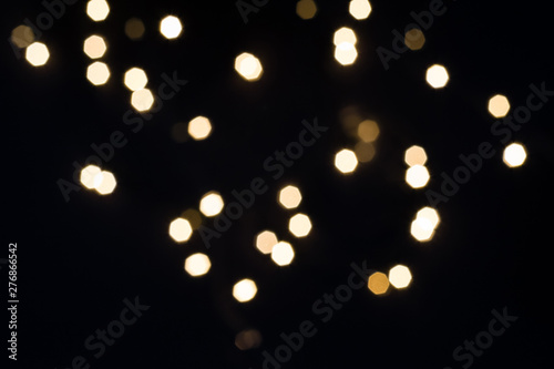 Gold bokeh lights falling on black. Holiday concept