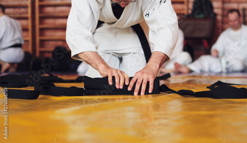 Color image of aikido. The male athlete carefully folds the black hackam. The traditional form of clothing in Aikido.