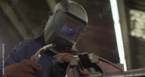 4K Female industrial worker welding steel in factory workshop. Slow motion.