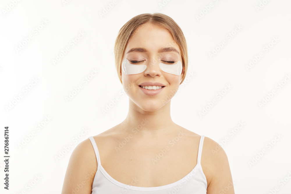 Beautiful girl uses eye patches on white background Beautiful girl uses eye patches on white background