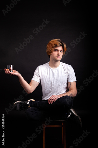 Young caucasian adult with blonde hair holding whiskey in hand © frimufilms