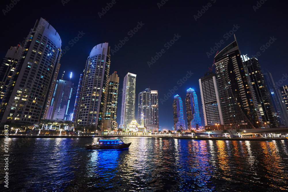 Naklejka premium Dubai Marina at night with colorful touristic boats