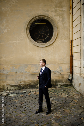 one groom poses near the old church