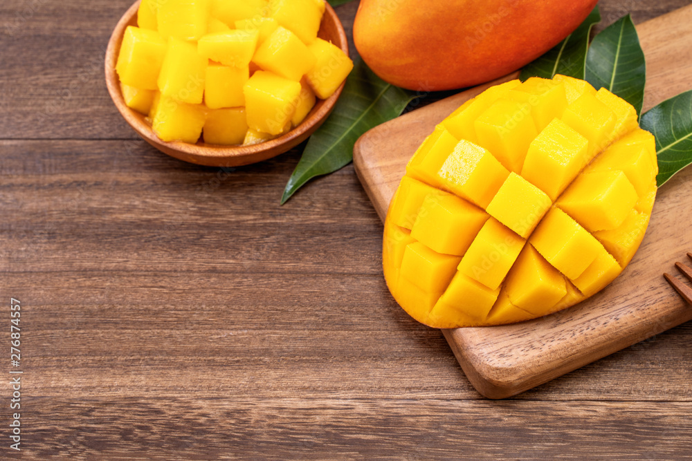 Fresh chopped mango cubes on wooden cutting board and rustic timber background. Tropical summer fruit concept, close up, macro, copy space. Fresh chopped mango cubes on wooden cutting board and rustic timber background. Tropical summer fruit concept, close up, macro, copy space.