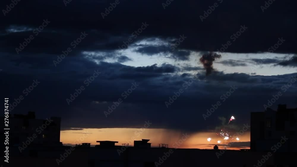 Festive salute against a dark blue lead sky after sunset. Colored lights. At dusk, you can see the silhouettes of houses Festive salute against a dark blue lead sky after sunset. Colored lights. At dusk, you can see the silhouettes of houses