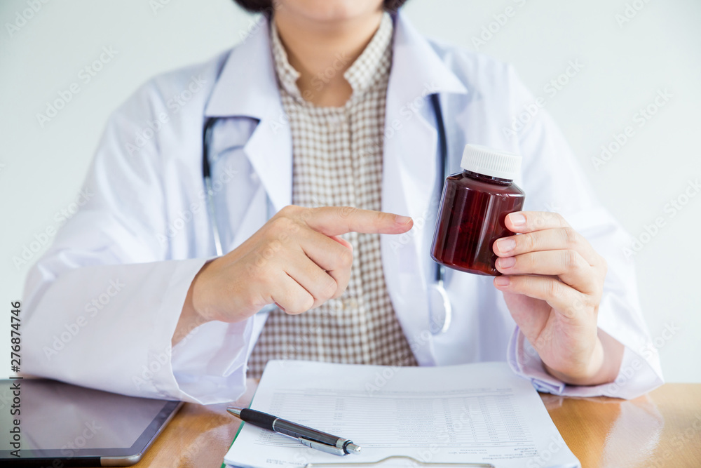 female doctor pointing on bottle of pills.healthy care concept. female doctor pointing on bottle of pills.healthy care concept.