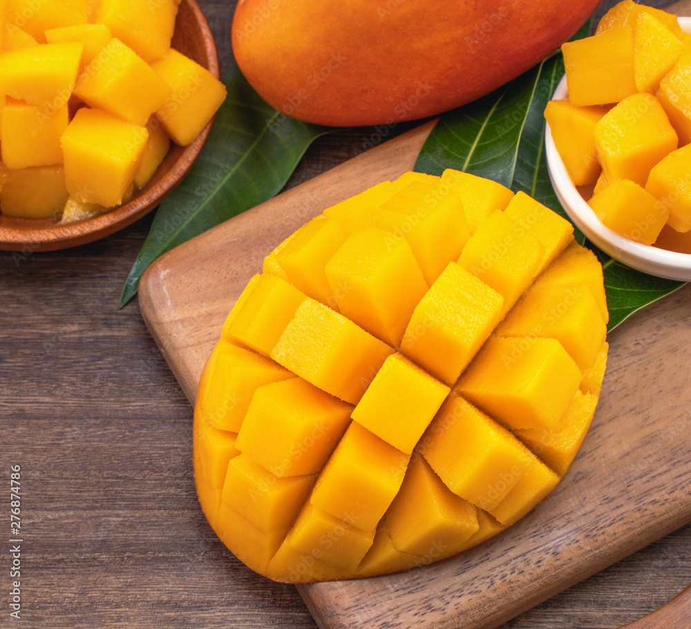 Fresh chopped mango cubes on wooden cutting board and rustic timber background. Tropical summer fruit concept, close up, macro, copy space. Fresh chopped mango cubes on wooden cutting board and rustic timber background. Tropical summer fruit concept, close up, macro, copy space.