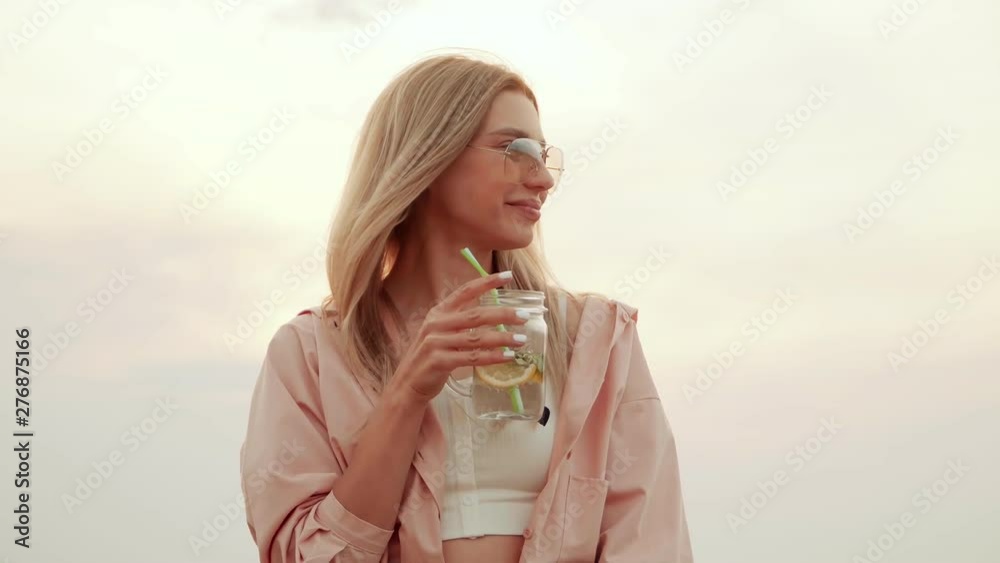 Girl with sunglasses drinking a delicious cocktail against the sky. summer urban cocktail Girl with sunglasses drinking a delicious cocktail against the sky. summer urban cocktail