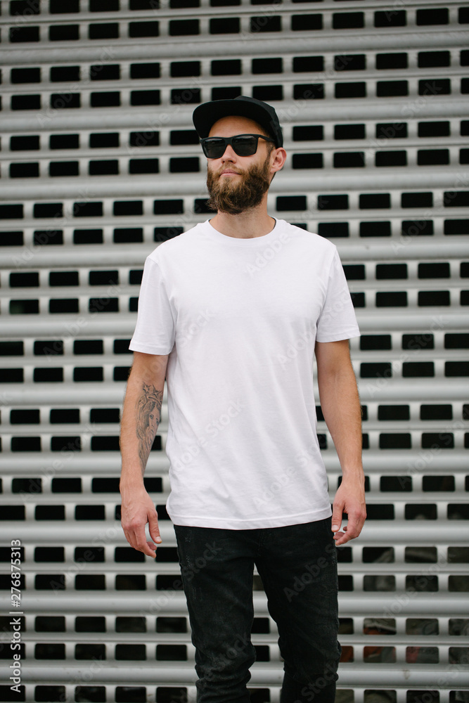 Hipster handsome male model with beard wearing white blank t-shirt and a baseball cap with space for your logo or design in casual urban style Hipster handsome male model with beard wearing white blank t-shirt and a baseball cap with space for your logo or design in casual urban style