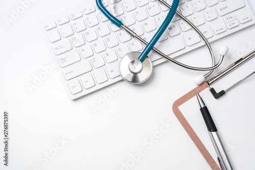 Stethoscope on computer keyboard on white background. Physician write medical case long term care treatment concept, top view, flat lay, copy space