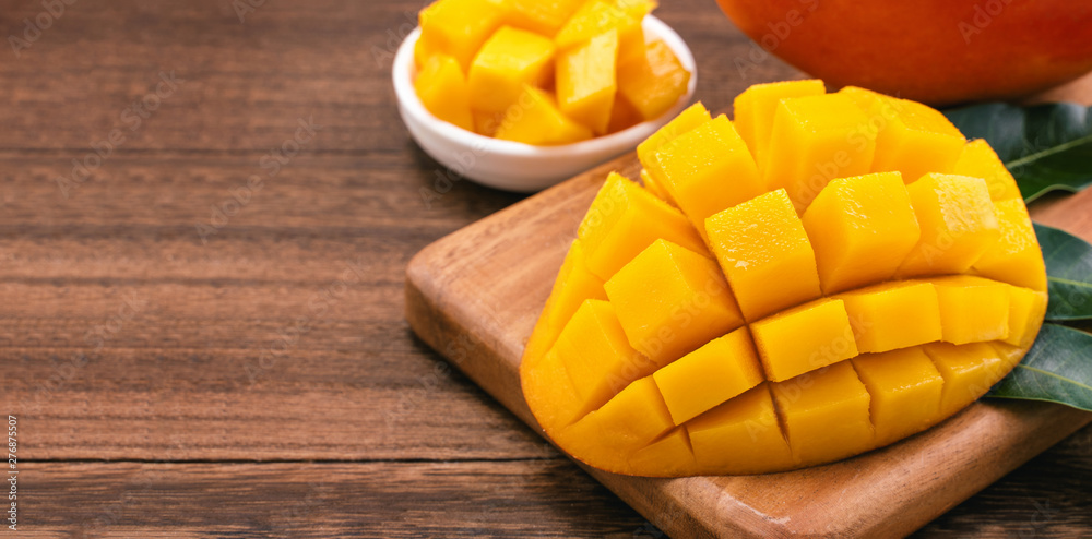 Fresh chopped mango cubes on wooden cutting board and rustic timber background. Tropical summer fruit concept, close up, macro, copy space. Fresh chopped mango cubes on wooden cutting board and rustic timber background. Tropical summer fruit concept, close up, macro, copy space.