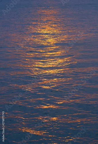 Beautiful reflection of the setting sun in ocean surface. Abstract nature background.