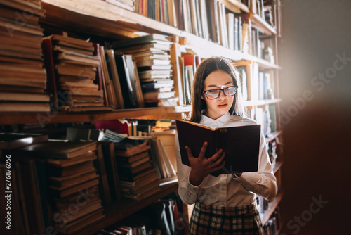 people, knowledge, education and school concept - student girl or young woman reading a book in the old library