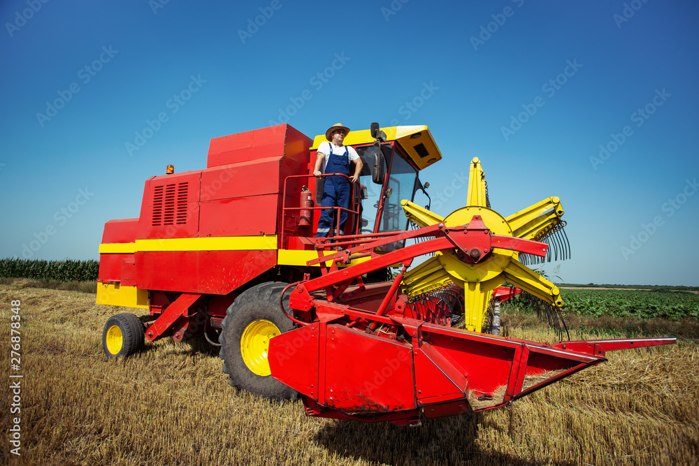 Fototapeta premium Farmer in wheat field with harvester