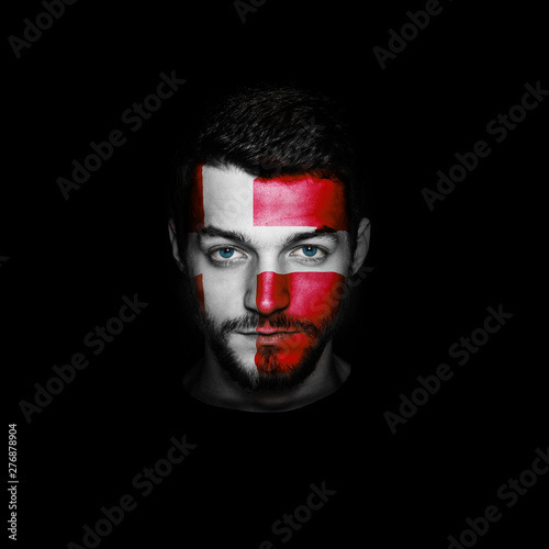Flag of Denmark painted on a face of a man on black background.
