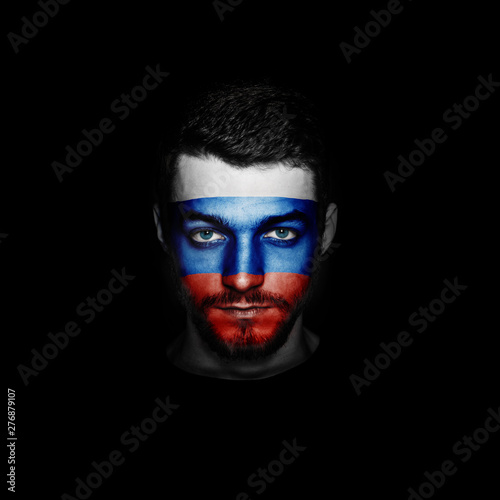 Flag of Russia painted on a face of a man on black background.