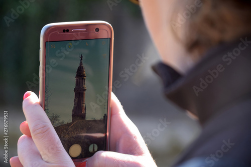 A tourist photographs the tower of the people in Palazzolo - Italy photo