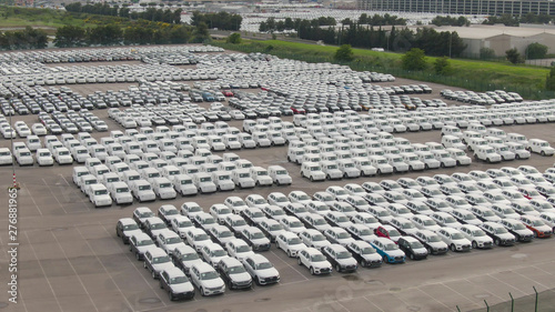 DRONE: Countless cars are neatly parked in lines in a large storage parking lot.