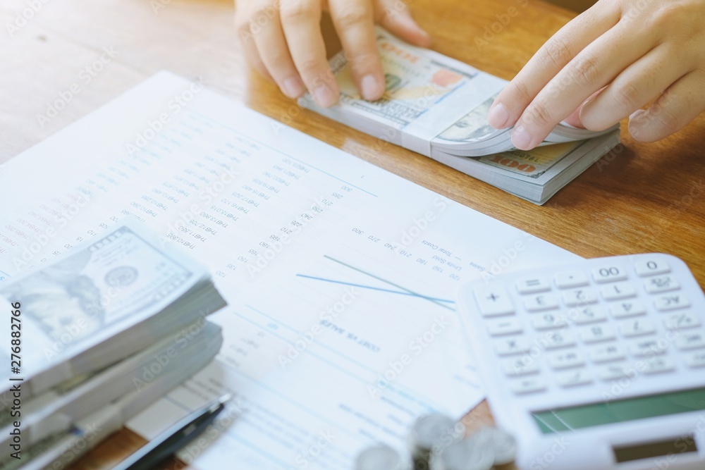 Obraz premium Businessman analyzing investment charts and pressing calculator buttons over documents. Accounting Concept.