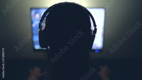 Gamer with Headphones in Dark Room playing Video Game at Night