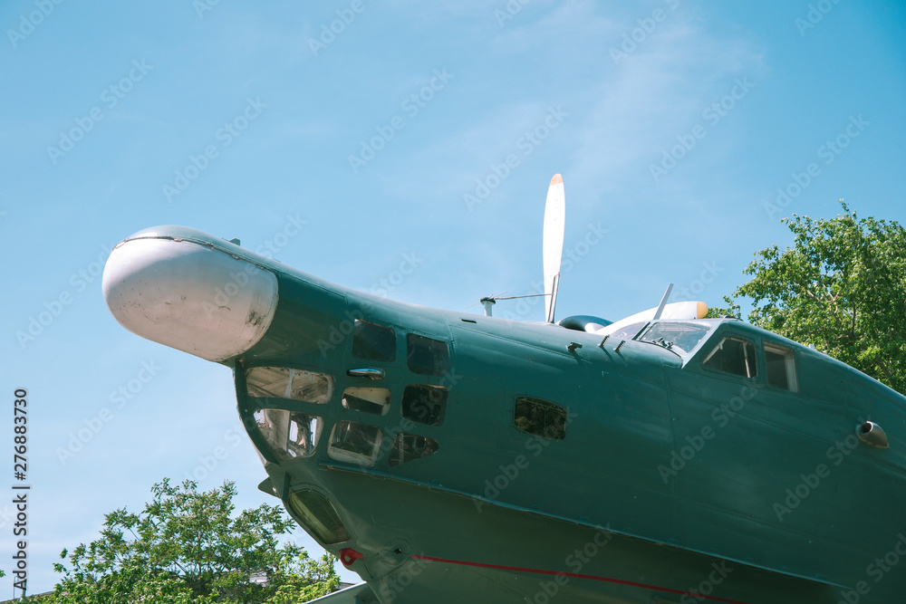 nose of the old military aircraft of green. Old military aircraft in green with white propellers against a blue sky. monument of military aircraft on the background of trees and sky nose of the old military aircraft of green. Old military aircraft in green with white propellers against a blue sky. monument of military aircraft on the background of trees and sky