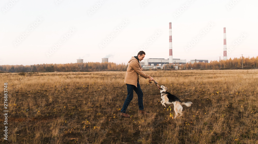Obraz premium A man with a mongrel dog walking on autumn meadow