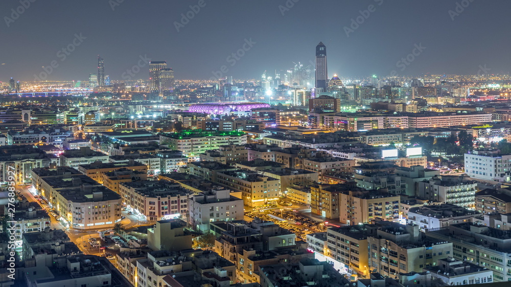 Fototapeta premium Aerial view of neighbourhood Deira with typical buildings night timelapse, Dubai, United Arab Emirates
