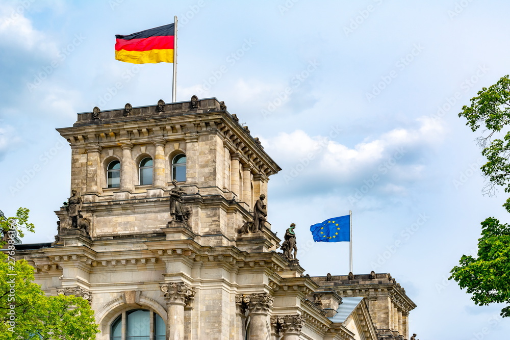 German and EU flags raising over Reichstag building (Bundestag - parliament of Germany) in Berlin